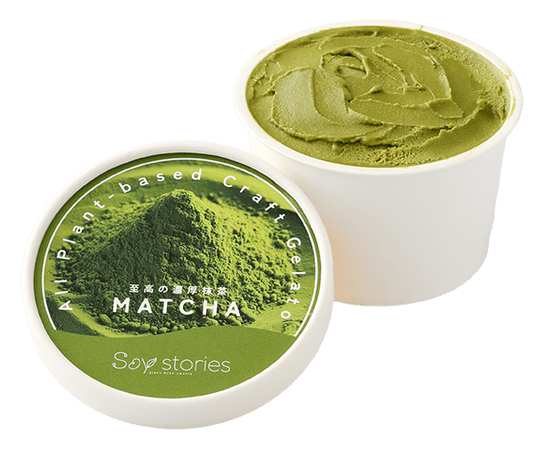 白い紙のカップに黄緑色のアイスクリームが入っている。その横には、抹茶粉の写真と商品名が印刷されたカップアイスの蓋が置かれている。
