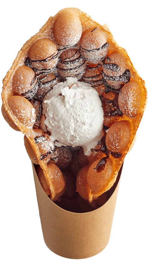 大きいサイズのワッフルホイップ。きつね色に焼かれ、チョコソースと粉糖がまぶされたバブルワッフルが軽く丸められている。その間に白いホイップクリームがアイスクリームのように丸められてトッピングされている。